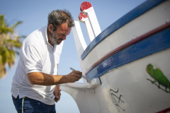 man painting traditional row boat with brush